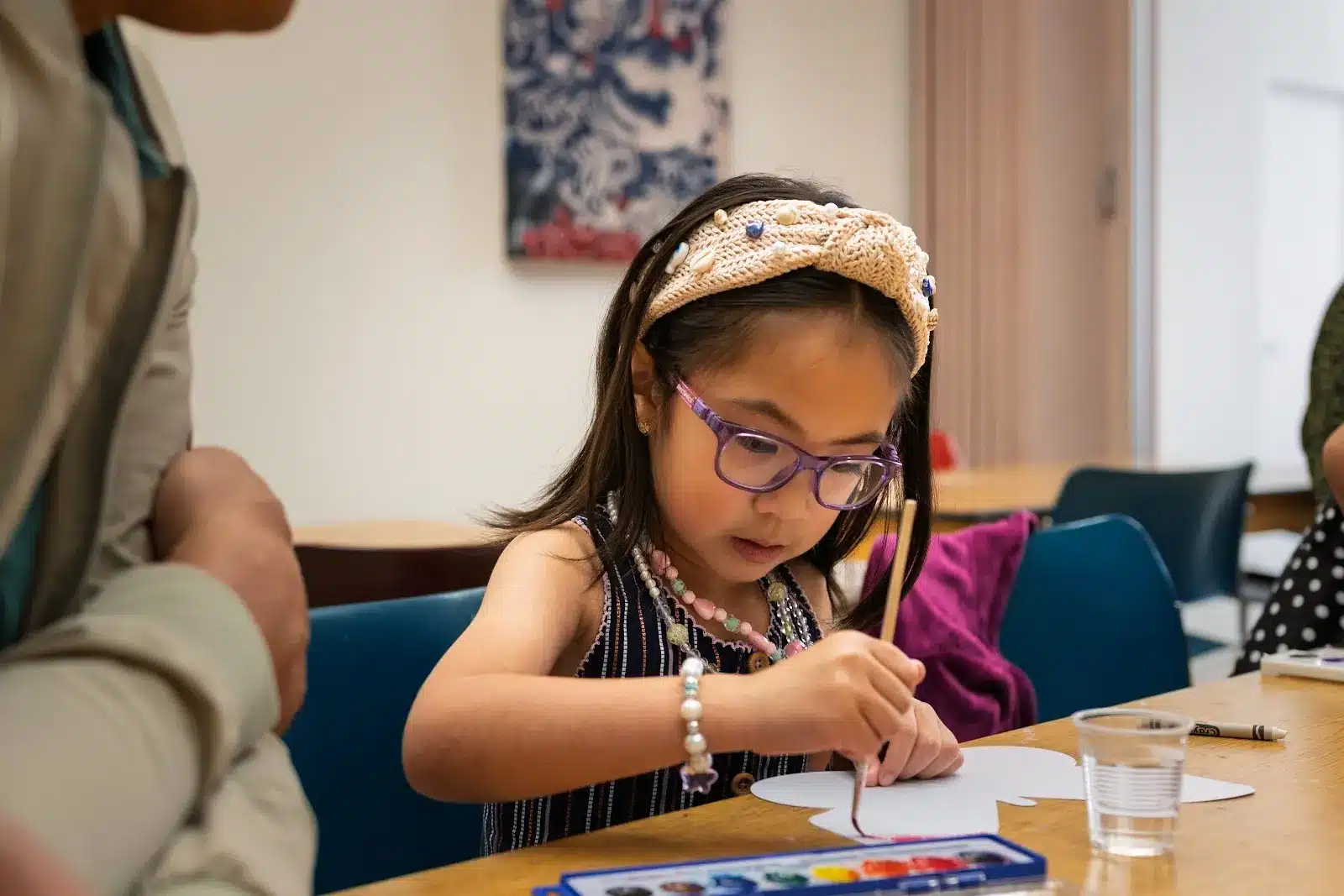 A child painting a paper shape with watercolors during a museum art activity.