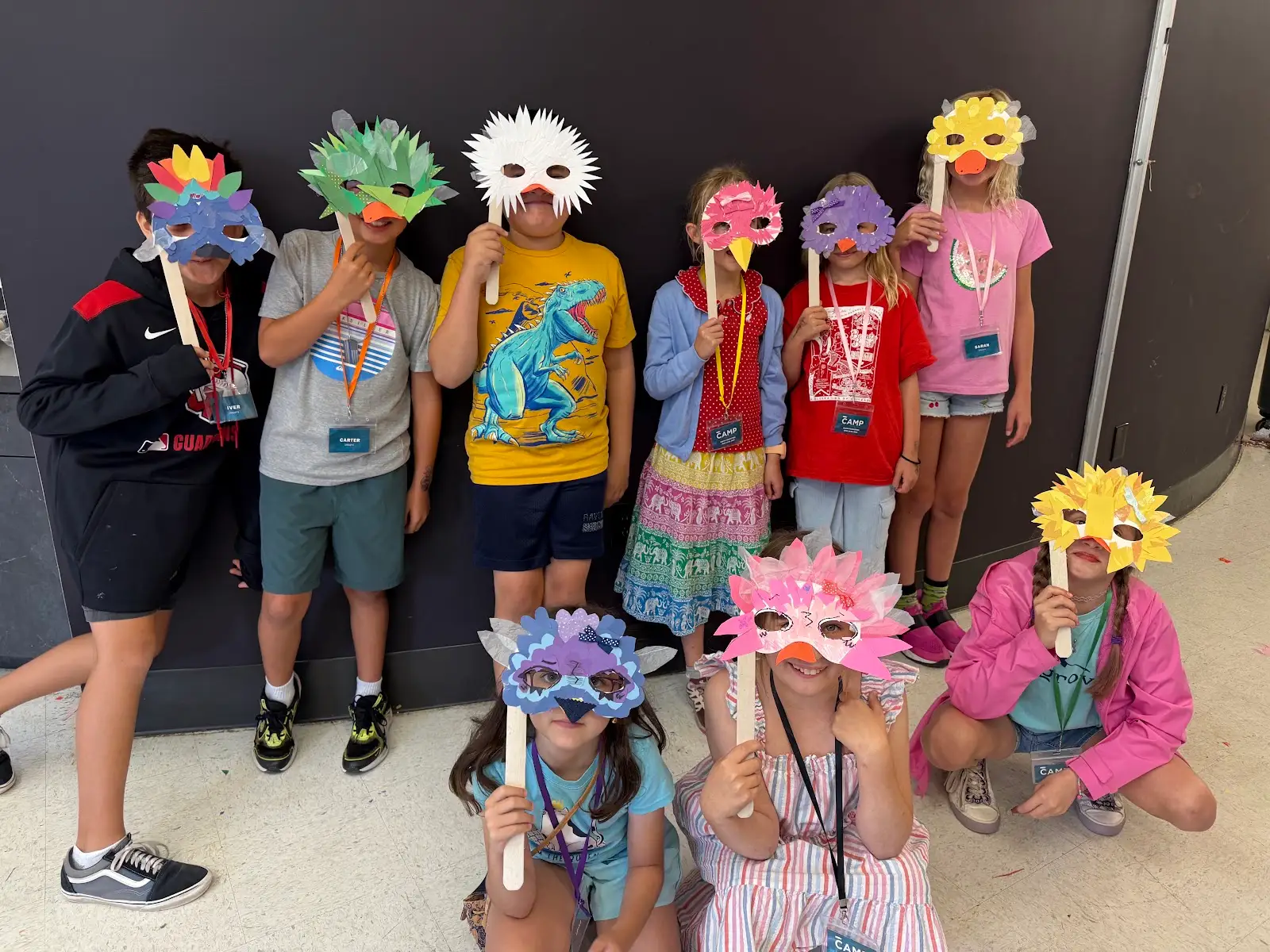 Children displaying colorful handmade animal masks during a museum art workshop.