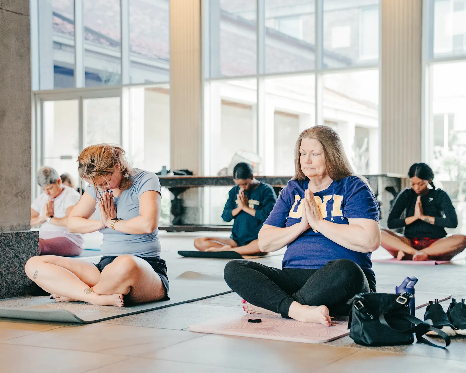 Participants seated on yoga mats with hands together during a museum yoga class.